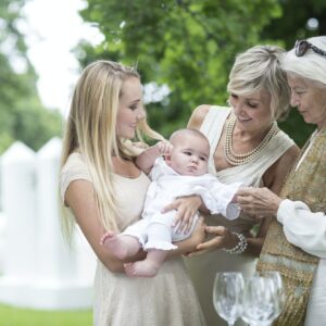 Three women gathering around baby outdoors